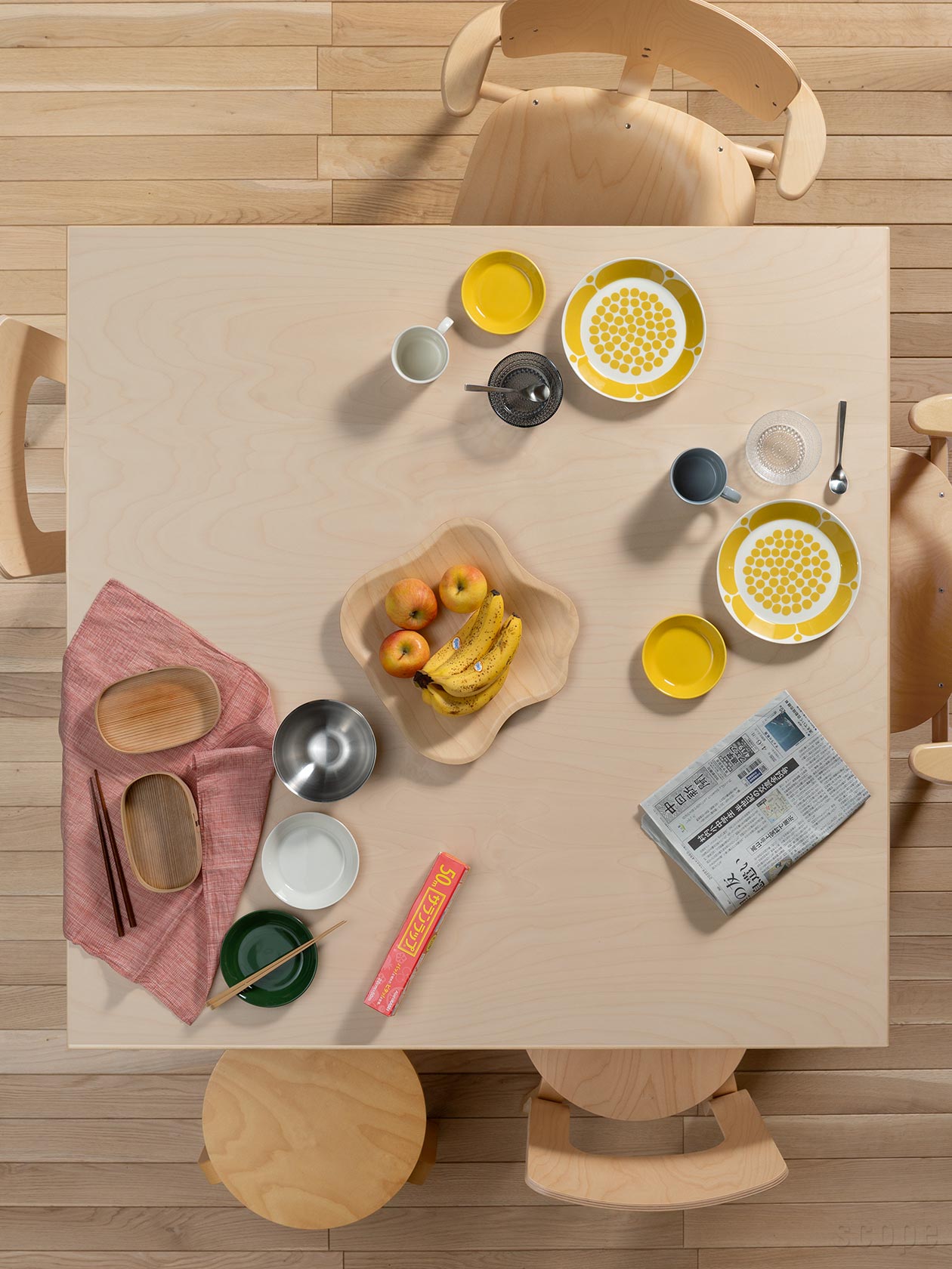 Artek（アルテック）84 テーブル ナチュラルラッカー。朝食の風景。バーチの天板に、Sunnuntaiイエロー、アアルトのボウル、新聞、サランラップが置かれている