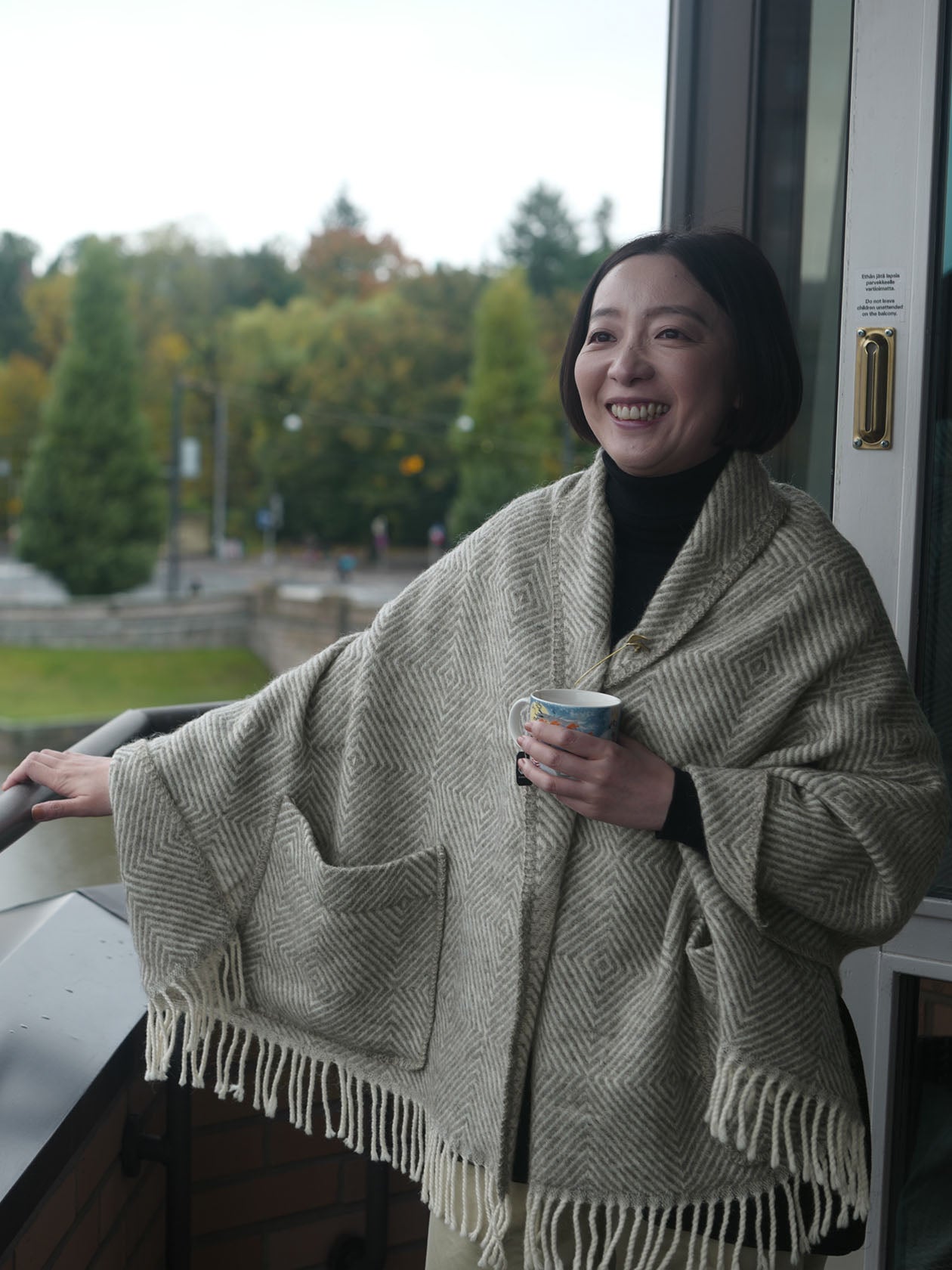 ショール ウィズ ポケット Maria グレーを羽織ってテラスでコーヒーを飲んでいるところ