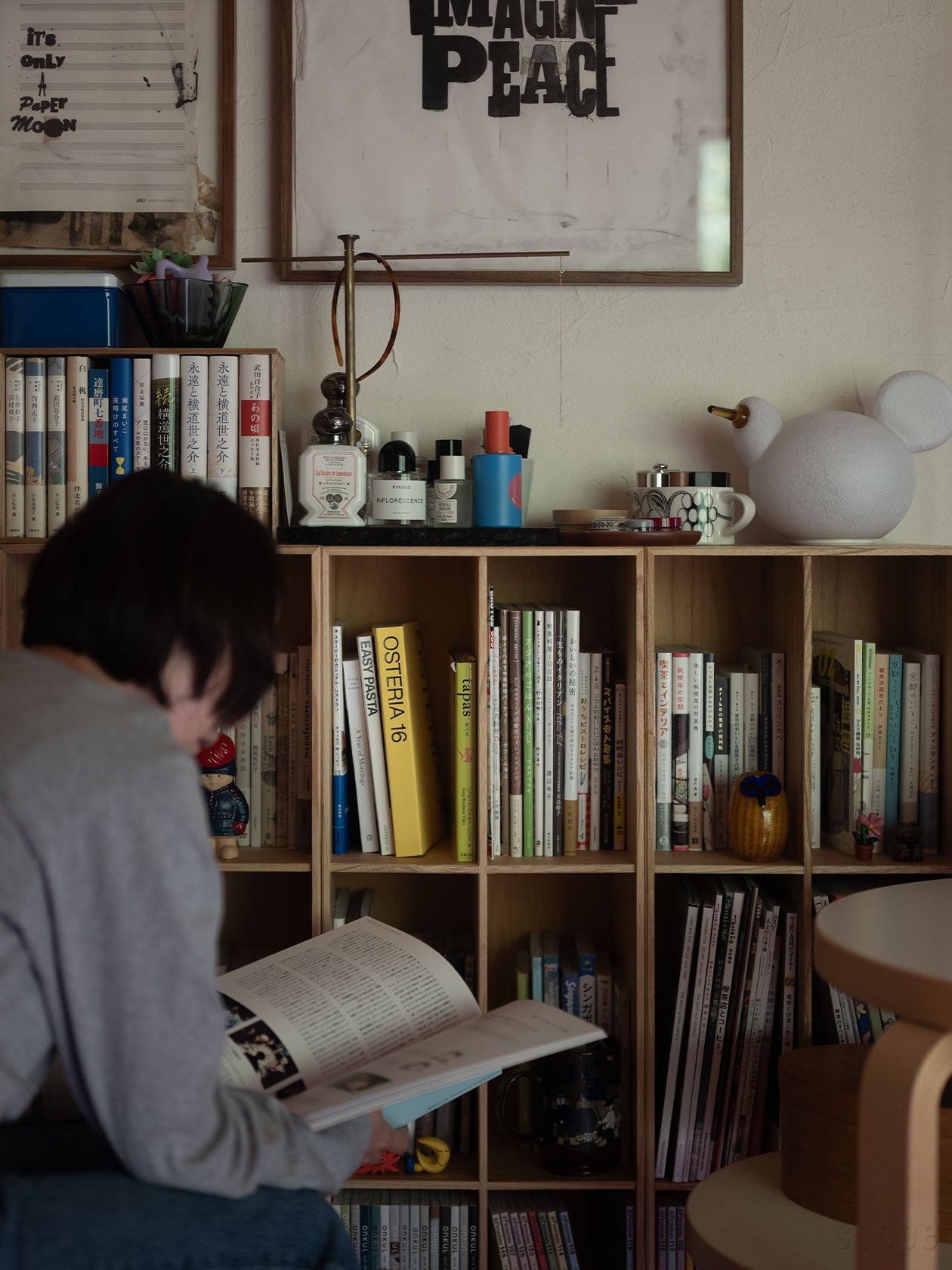 bookbookbook 1を壁面に並べて設置し、本を選んで読んでいるところ